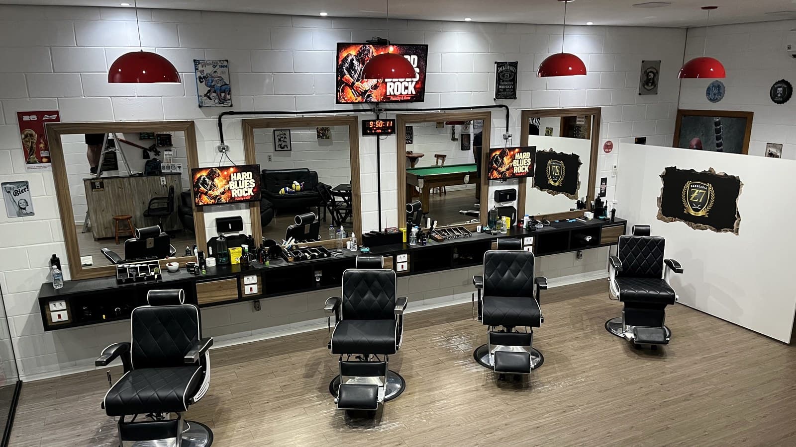 Salão da Z7 Barbearia com as quatro cadeiras, os espelhos e o brasão Z7 na parede